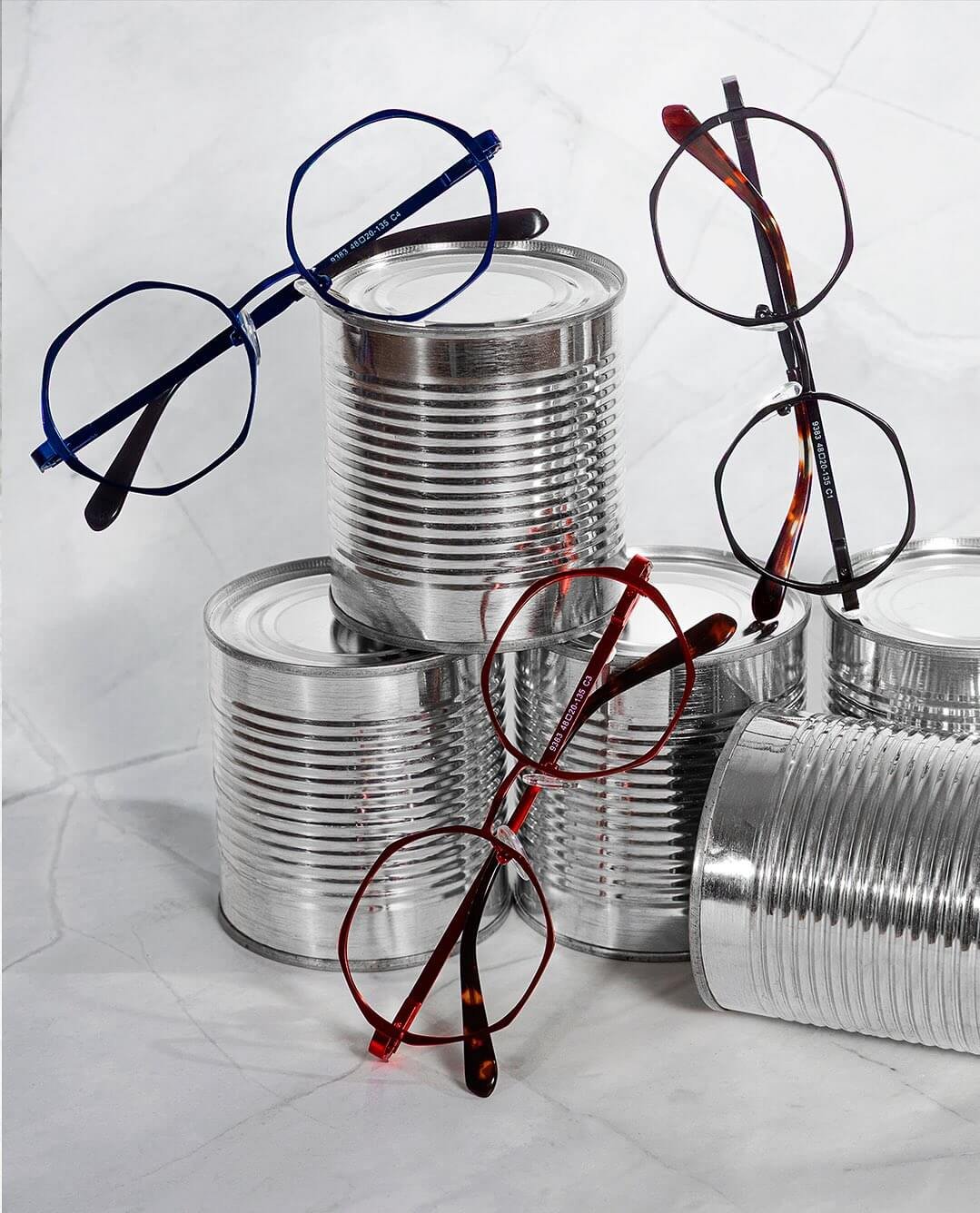 Armações de óculos metálicas finas alinhadas em suporte de bancada.