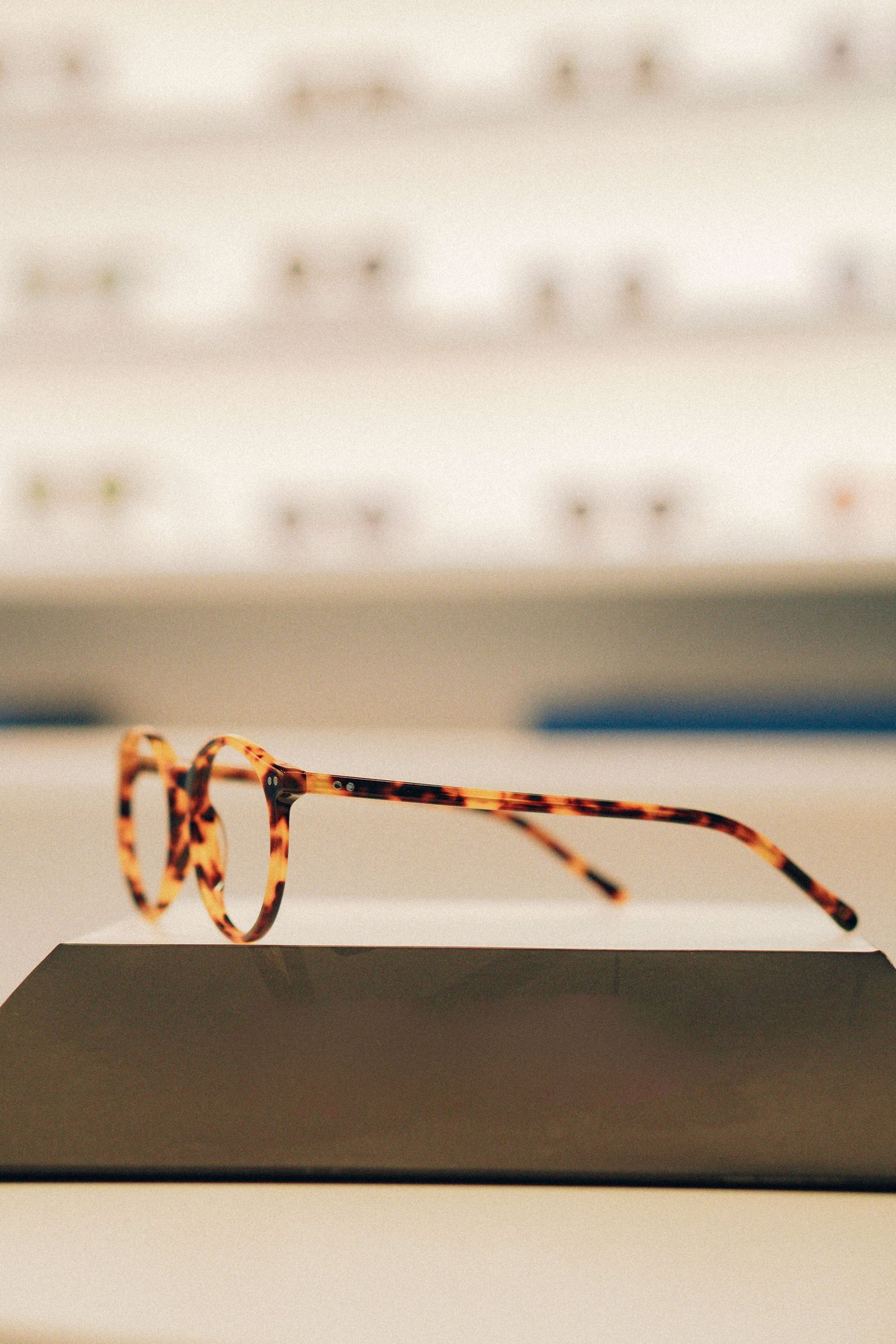 Mostruário com armações de óculos retangulares e redondas lado a lado.