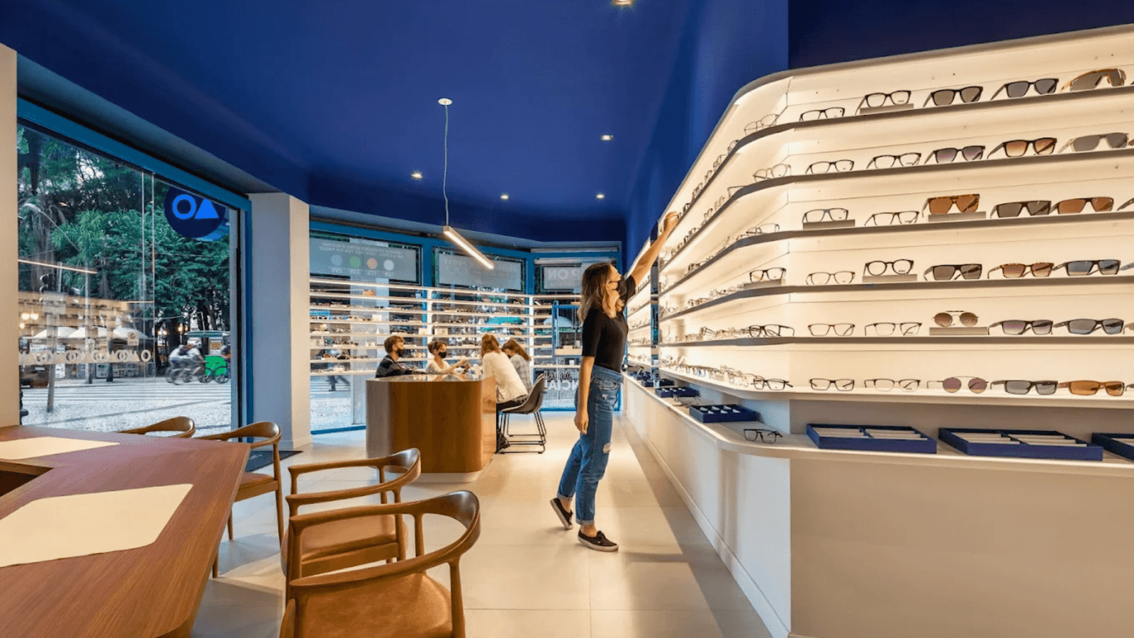 Interior da ótica OART em Curitiba com cliente escolhendo armações em prateleiras iluminadas.