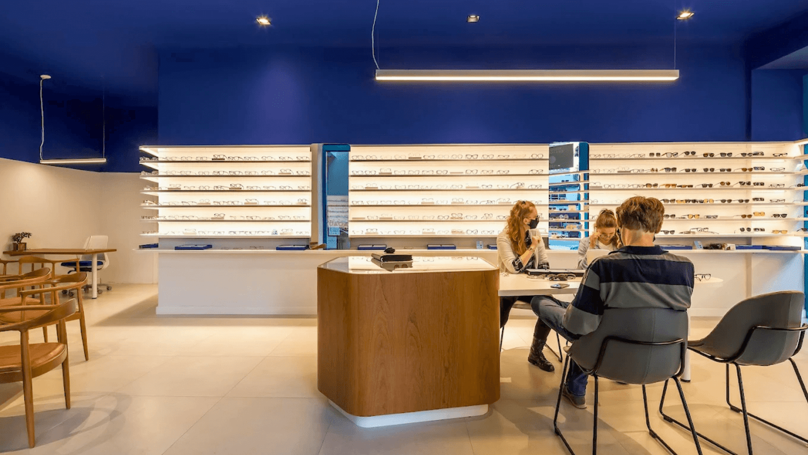 Balcão de atendimento em madeira com consultora auxiliando cliente dentro da ótica OART em Curitiba.