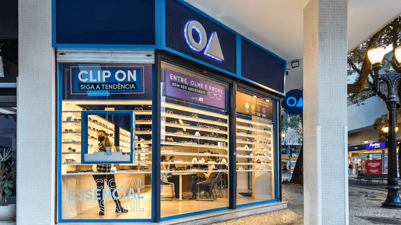 Fachada envidraçada da ótica OART em Curitiba com vitrines cheias de armações de óculos