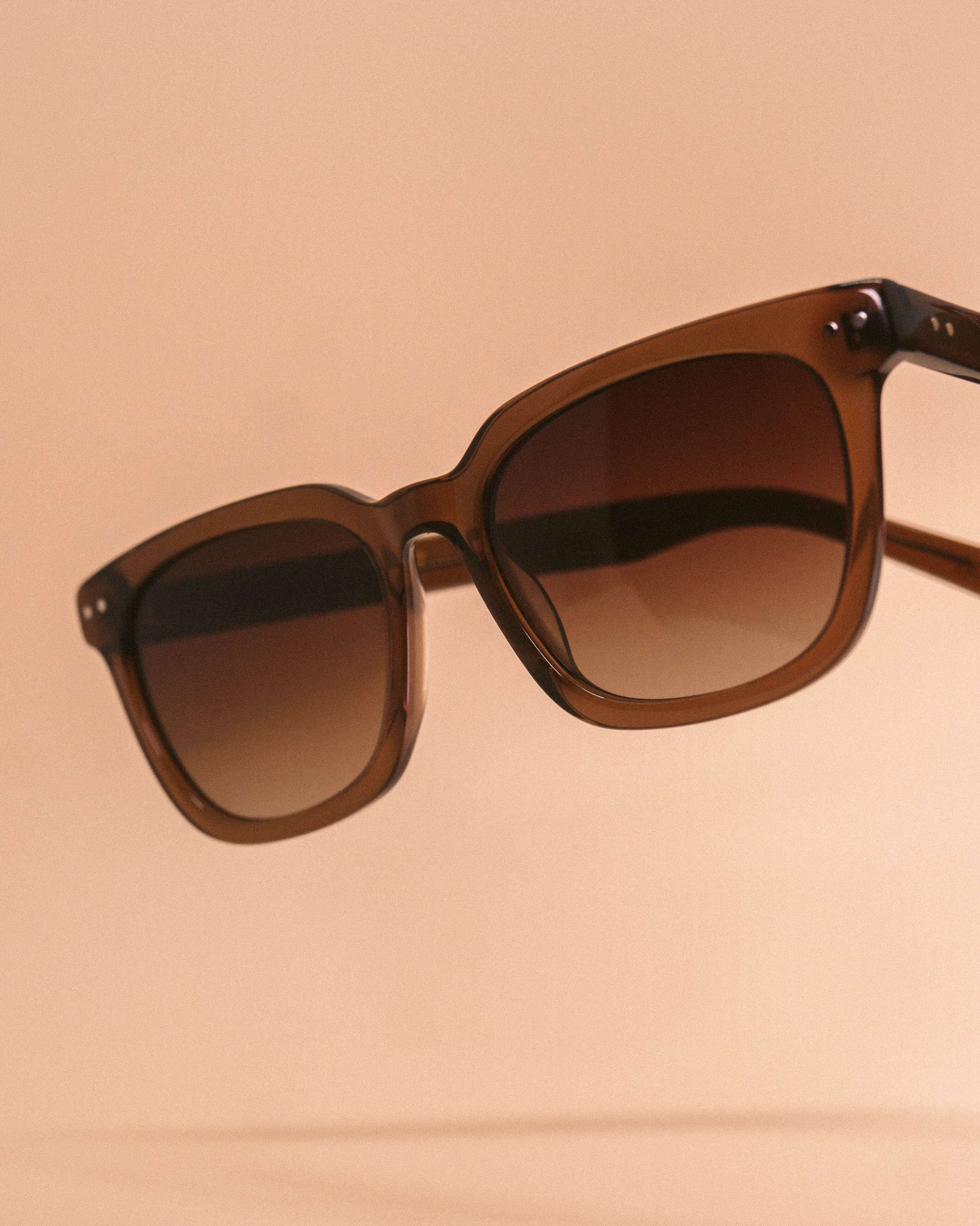 Óculos de sol em acetato tartaruga sobre fundo bege, em composição de produto.