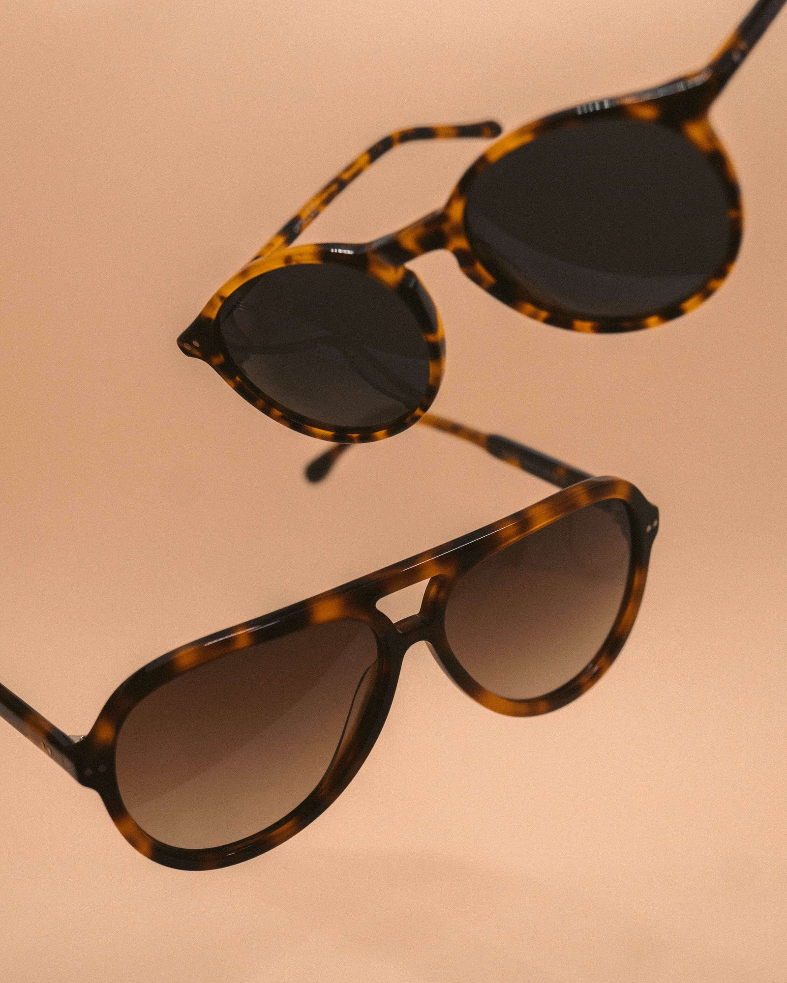 Conjunto de dois óculos de sol em acetato padrão tartaruga sobre fundo bege, em diferentes formatos de armação.